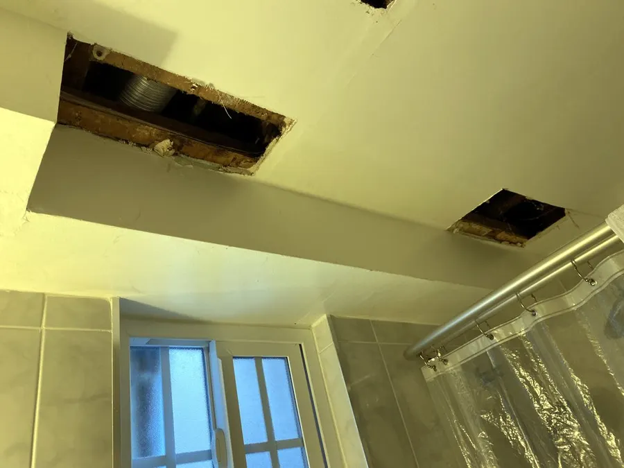 Bathroom ceiling with two drywall openings cut for access before patching
