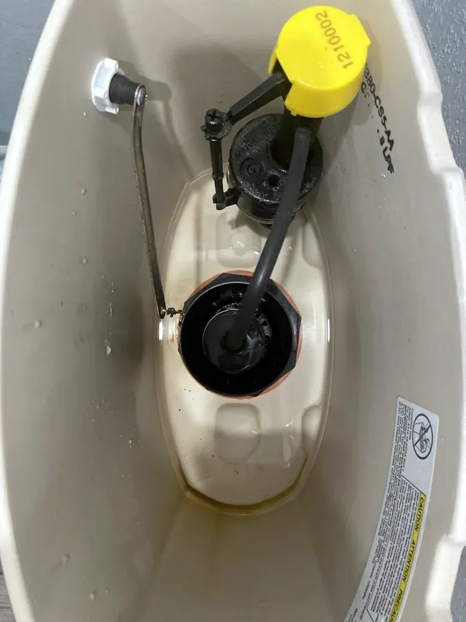 Inside a toilet tank with a new fill valve and flapper installed