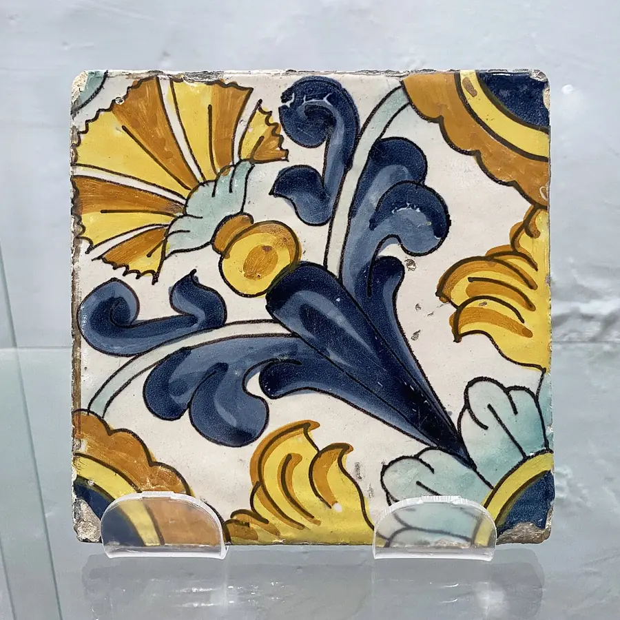 Single hand-painted ceramic tile with a blue and yellow leaf design