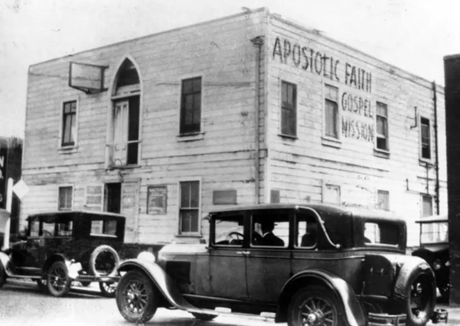 Old two-story wood-sided church building with vintage cars parked outside in Azusa