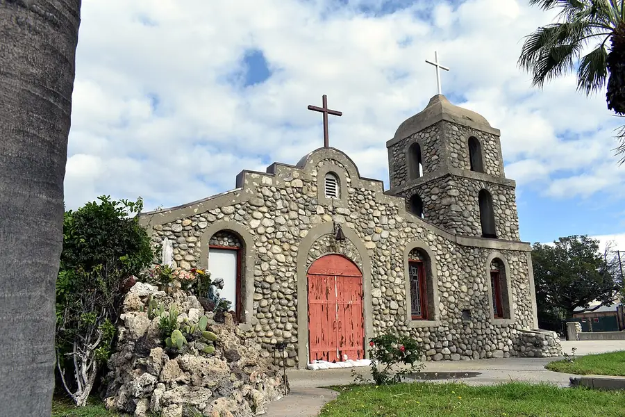 Historic stone mission chapel with a bell tower and red doors in Irwindale