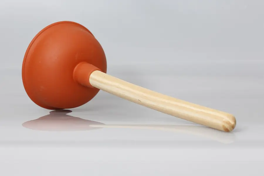 Red rubber cup plunger with a wooden handle