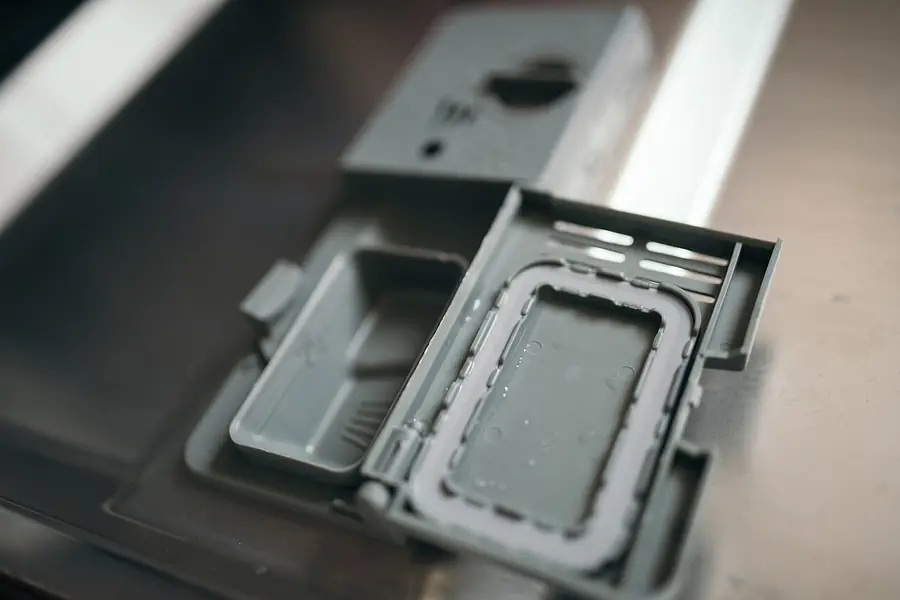 Close view of the gray detergent compartment on the inside of a dishwasher door