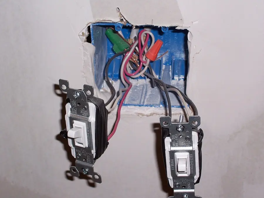 Two light switches pulled from their box showing the wiring