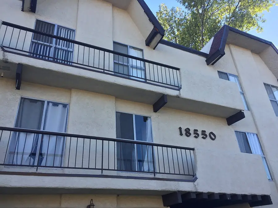Three-story apartment building with black metal balconies under a blue sky