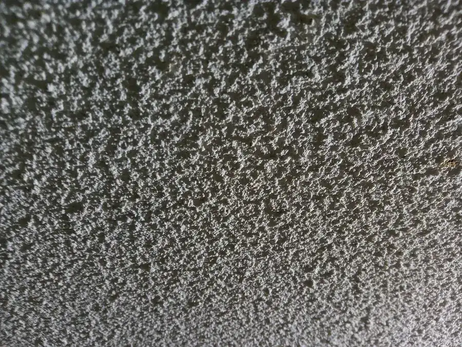 Close view of a white popcorn ceiling texture with rough bumpy surface