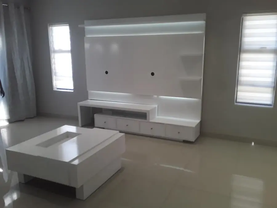 White wall-mounted TV unit with shelves in a living room