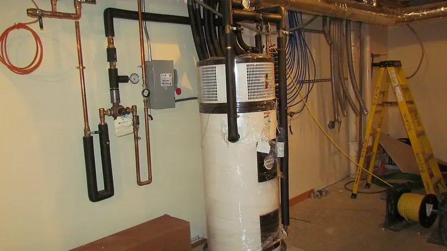 Electric tank water heater with insulated pipes in a basement utility room
