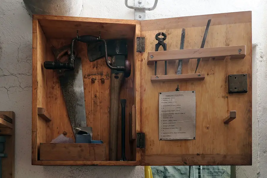 Hand tools hung inside a wooden wall cabinet in a workshop