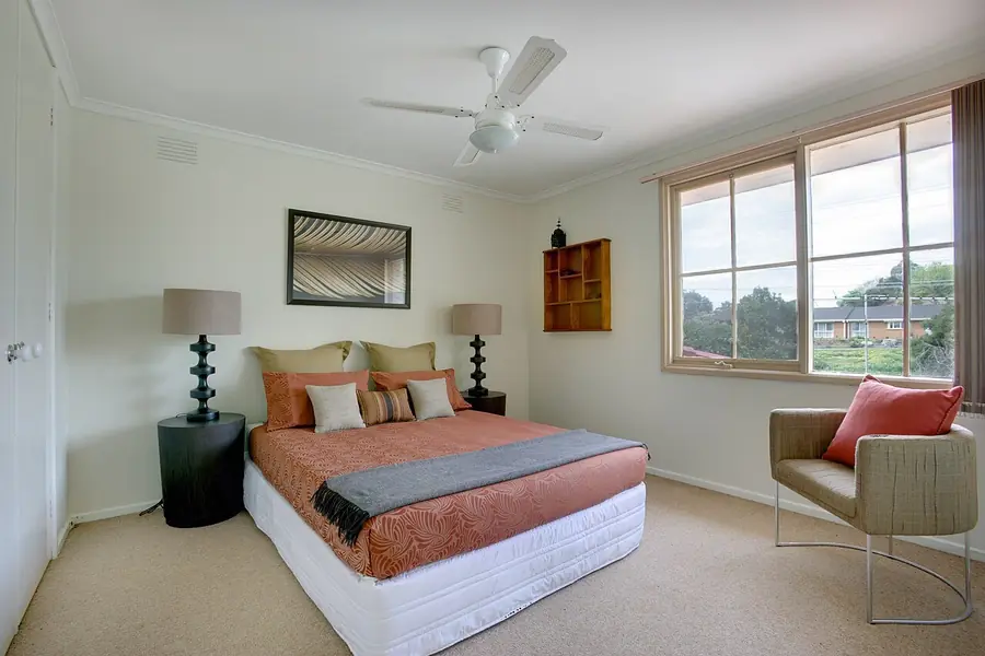 White ceiling fan with a light kit above a made bed in a bedroom