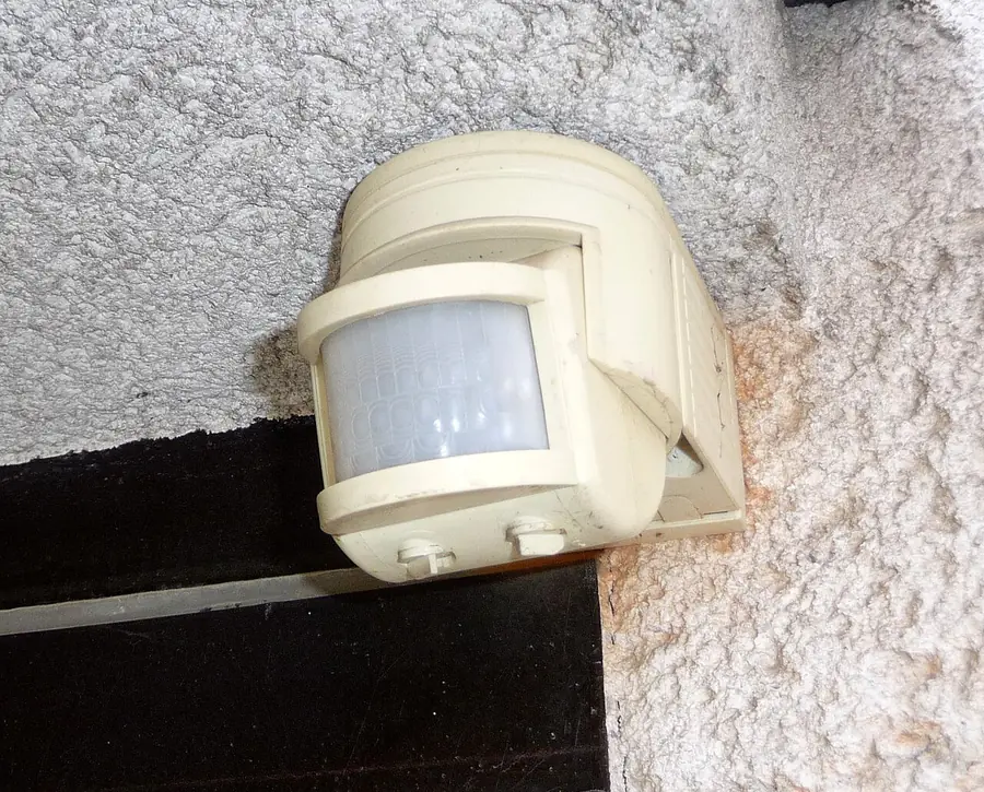 Motion detector sensor attached under an outdoor light on a house wall