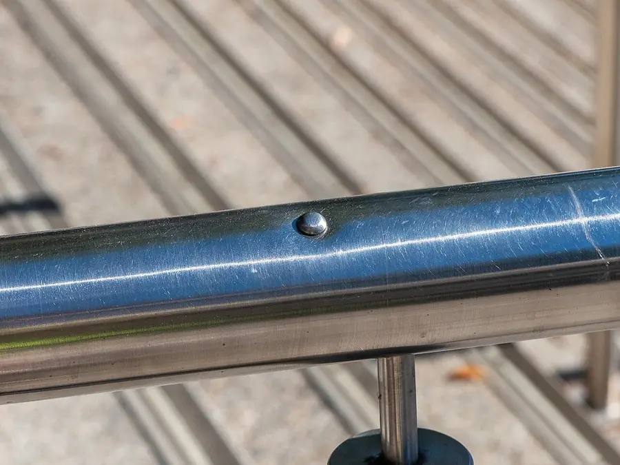Close view of a round metal stair handrail with a raised joint