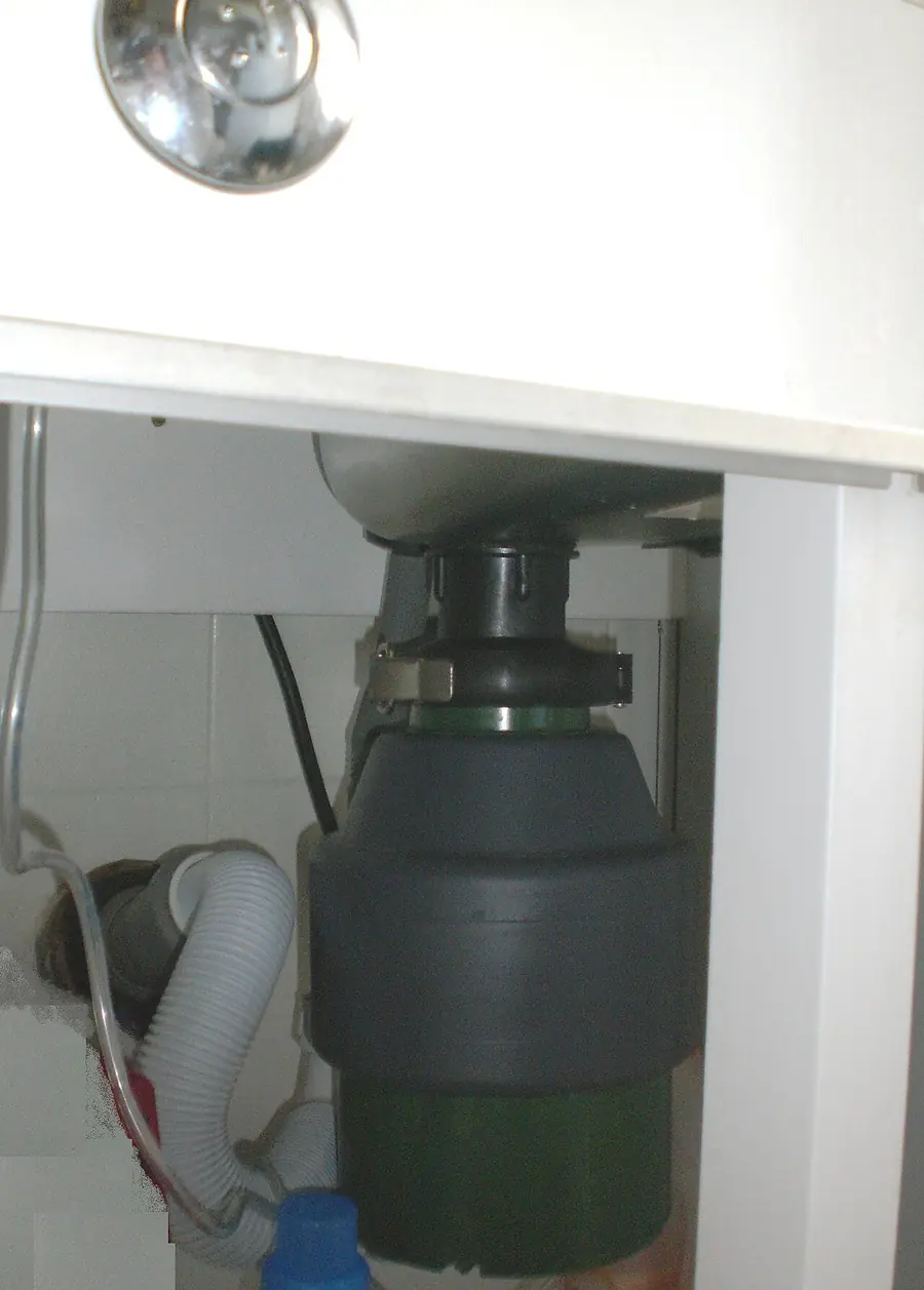 Food waste disposer installed under a kitchen sink inside a cabinet