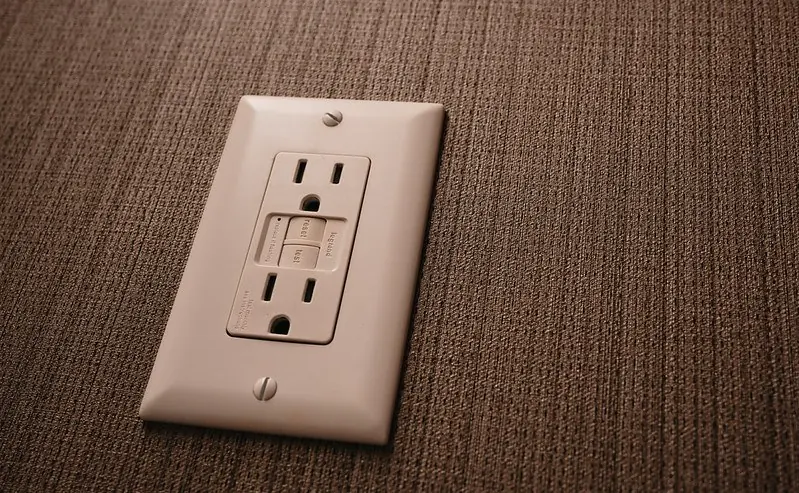 White GFCI outlet with test and reset buttons on a textured wall
