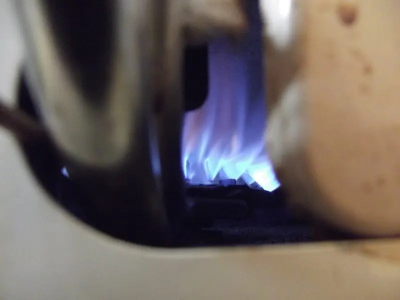 Blue gas burner flame glowing inside the bottom of a water heater