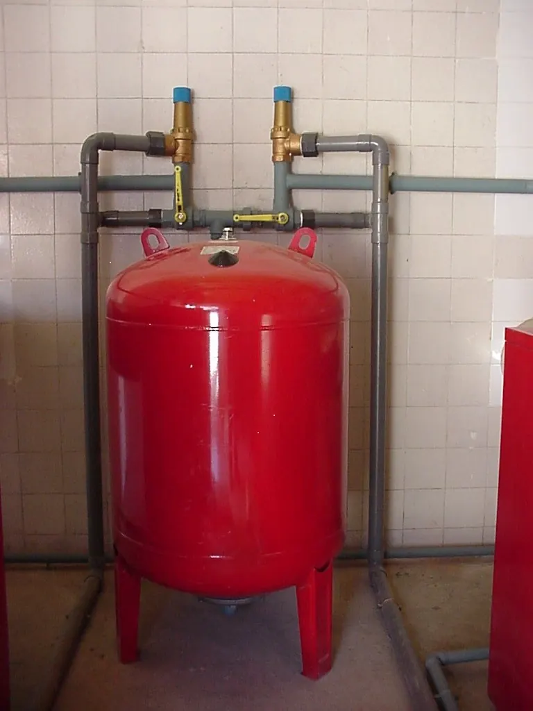 Red expansion tank mounted on hot water piping with shutoff valves