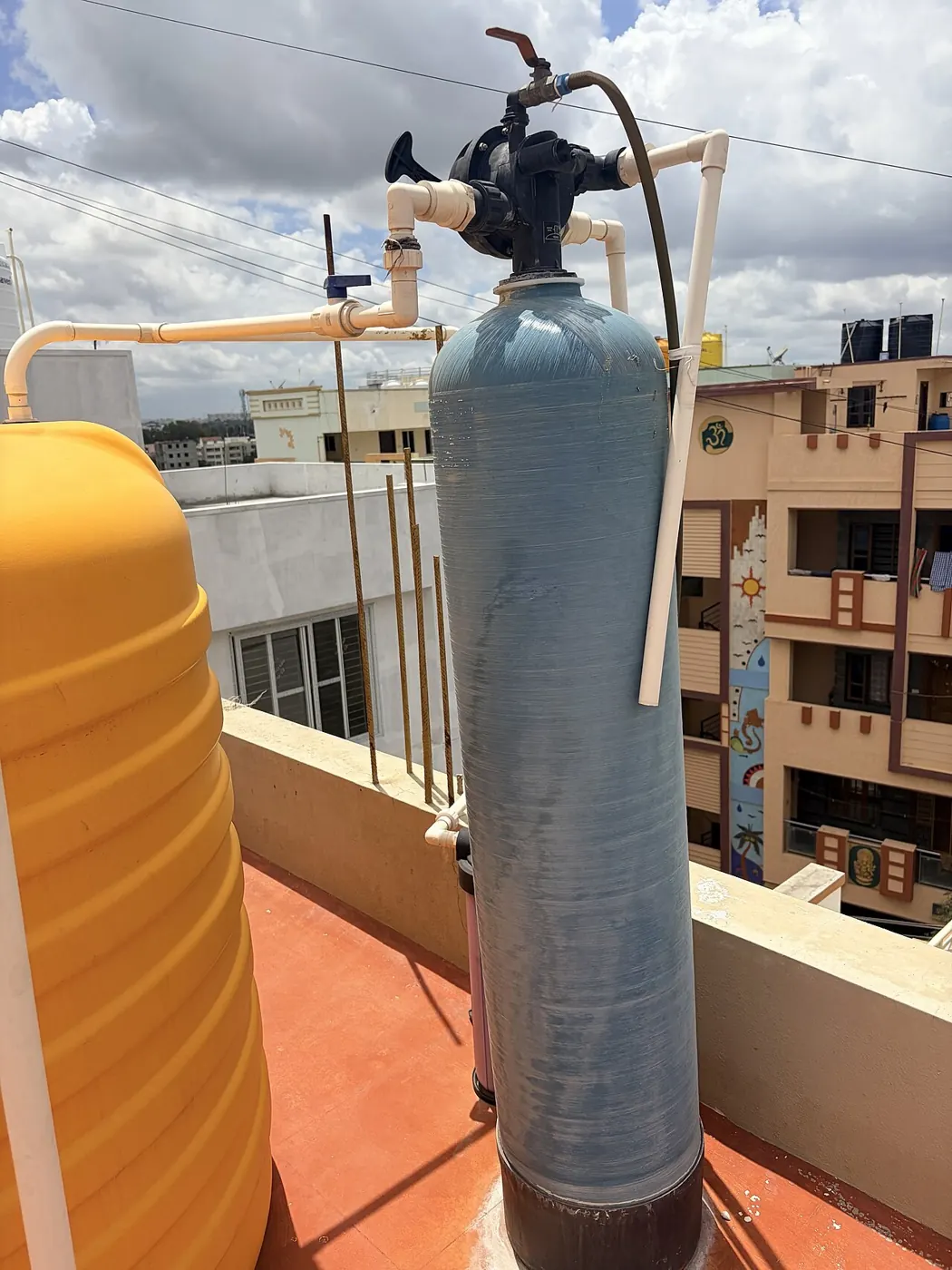 Water softener resin tank with a control valve and plastic piping on a rooftop