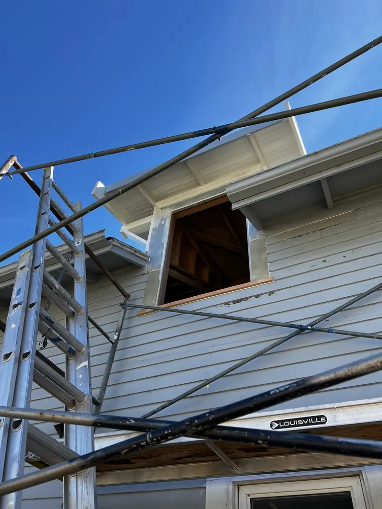 House siding with freshly caulked window trim, seen from scaffolding