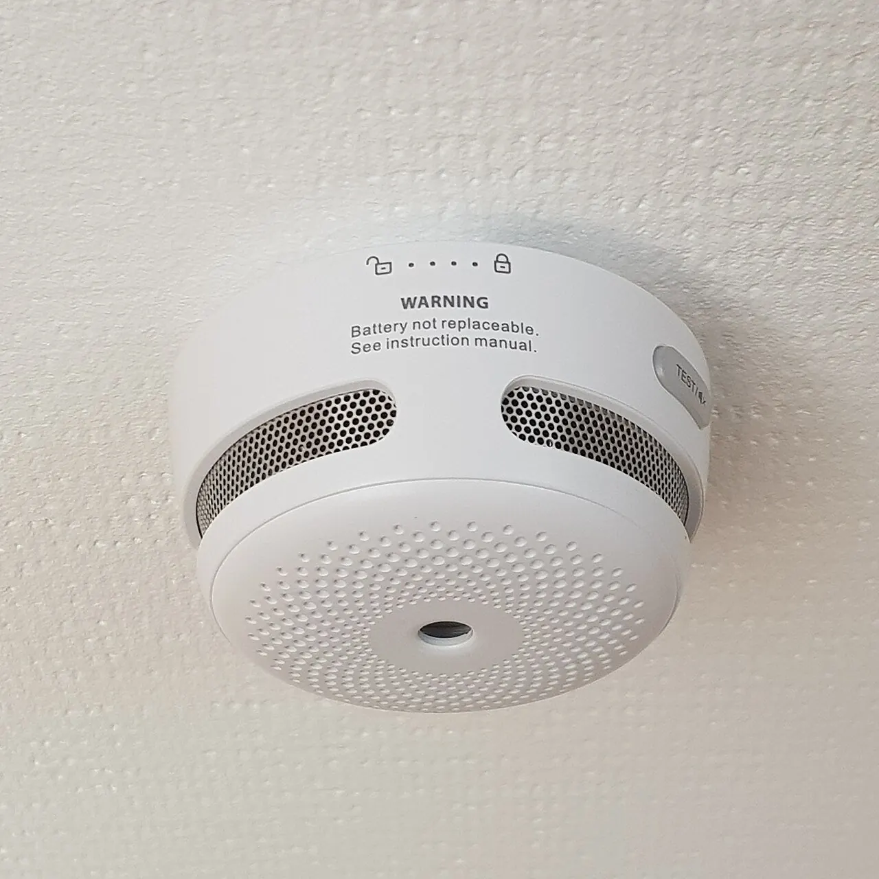 White smoke alarm mounted on a ceiling