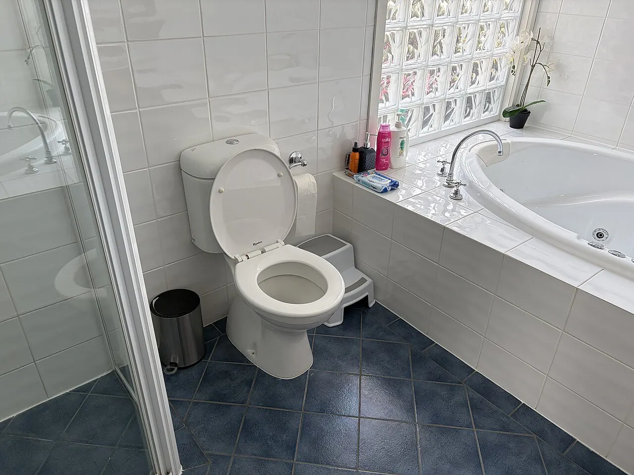 Toilet with a tank in a small bathroom next to the shower