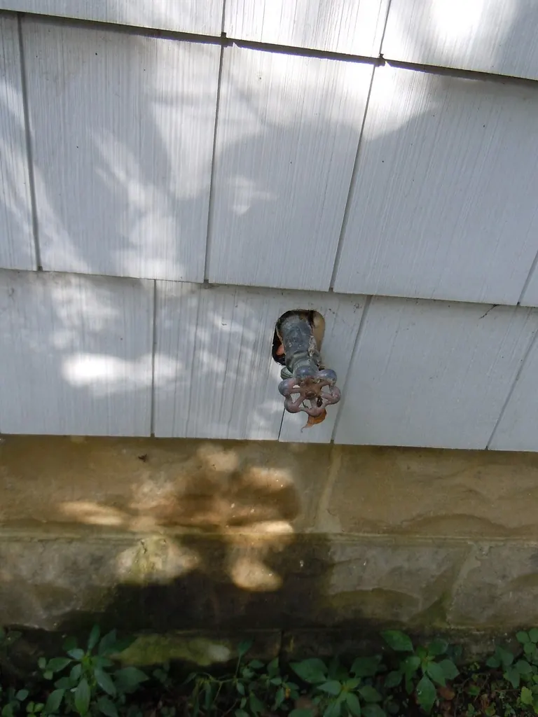 Outdoor hose bib on a house wall with a gap around it