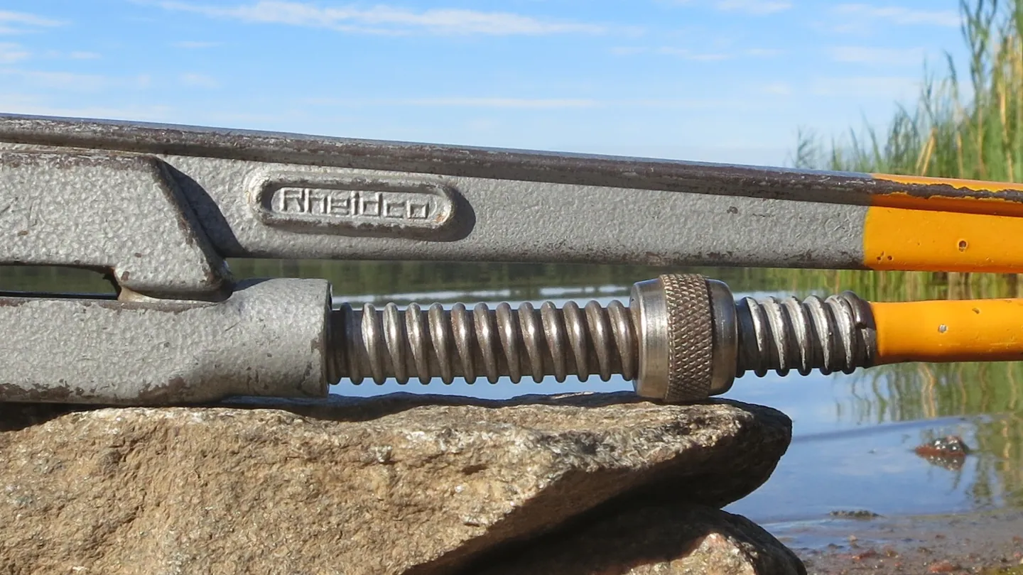 Two pipe wrenches resting on a rock by the water