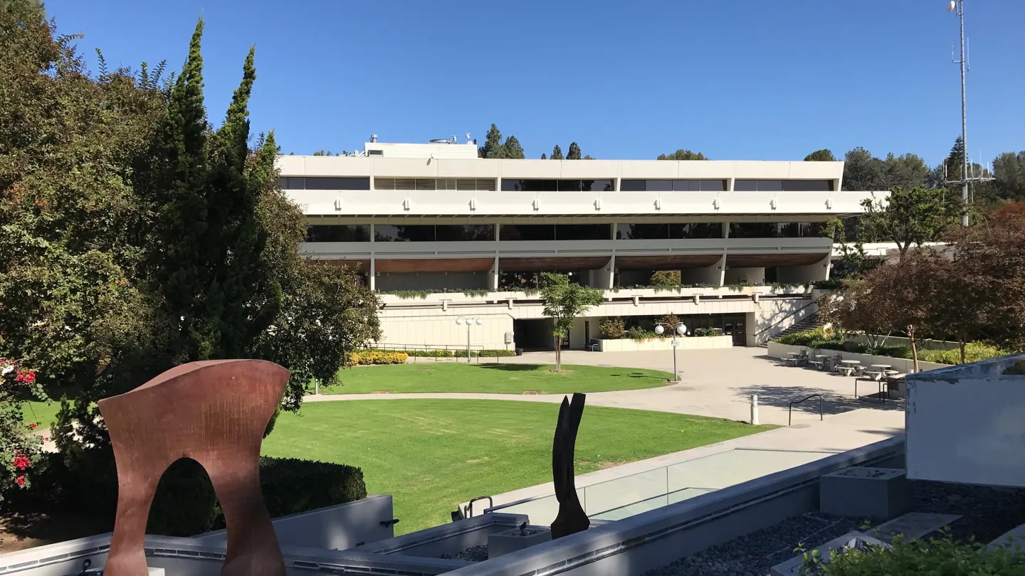 Low civic center building, lawn and outdoor sculpture in West Covina