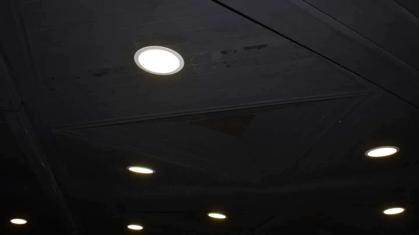 Flush round LED downlights glowing in a dark wood ceiling