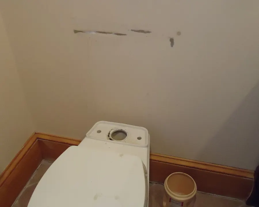 Toilet tank with the lid off in a small bathroom