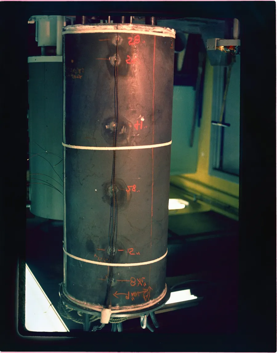 Tall copper-clad electric water heater tank standing in a dim room
