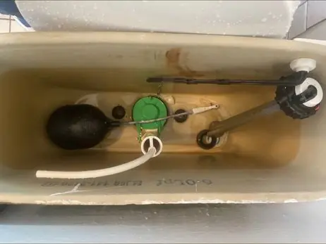 Inside a toilet tank showing the flapper, flush valve and fill valve