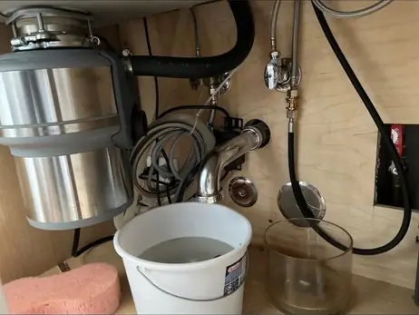 New garbage disposal under a sink with a bucket below
