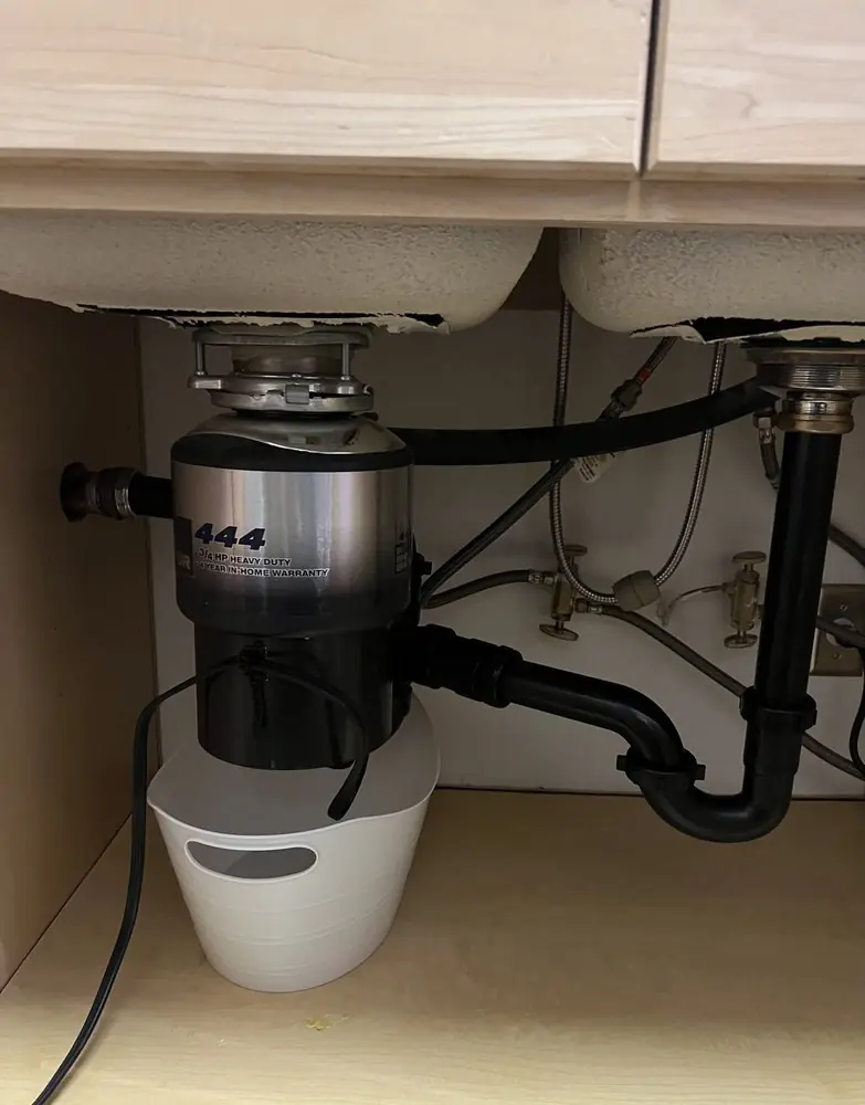 New garbage disposal mounted under a kitchen sink with the drain connected