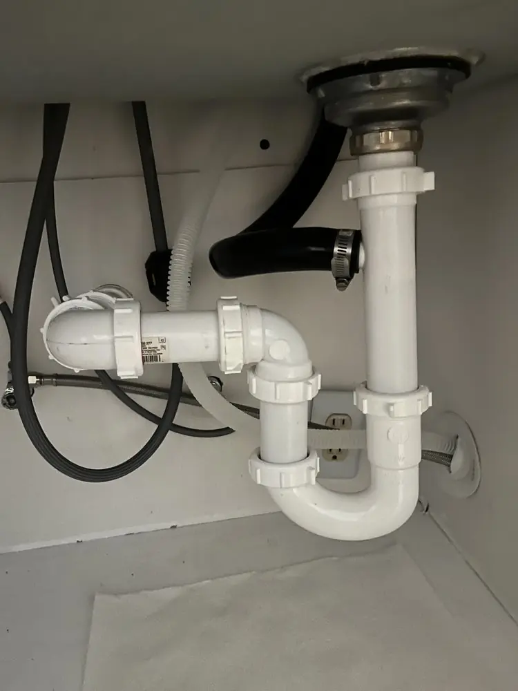 New white PVC P-trap and drain connections under a sink