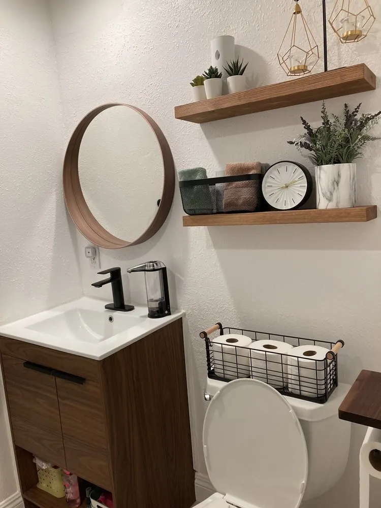Round mirror and two floating shelves hung above a small vanity