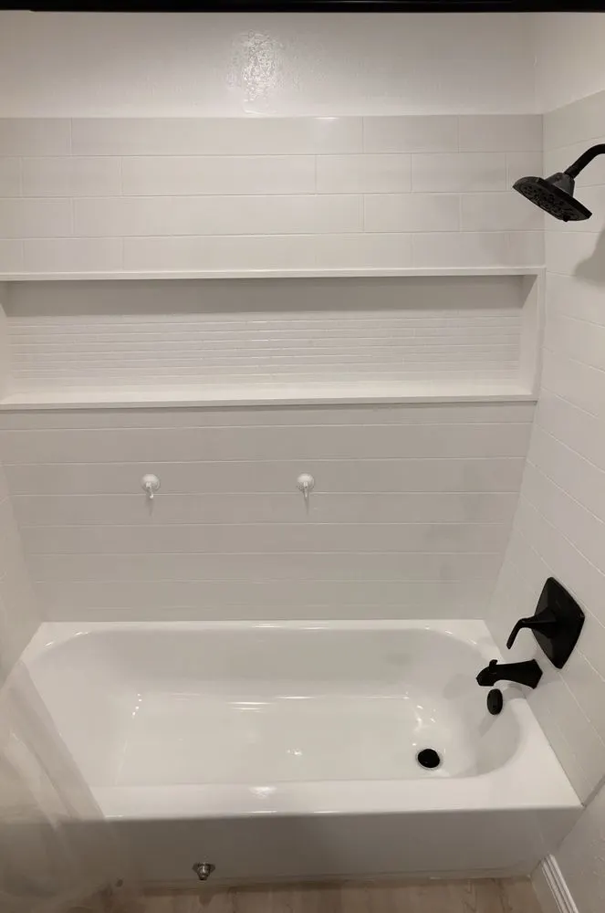 White tub with matte black spout and shower head, freshly sealed
