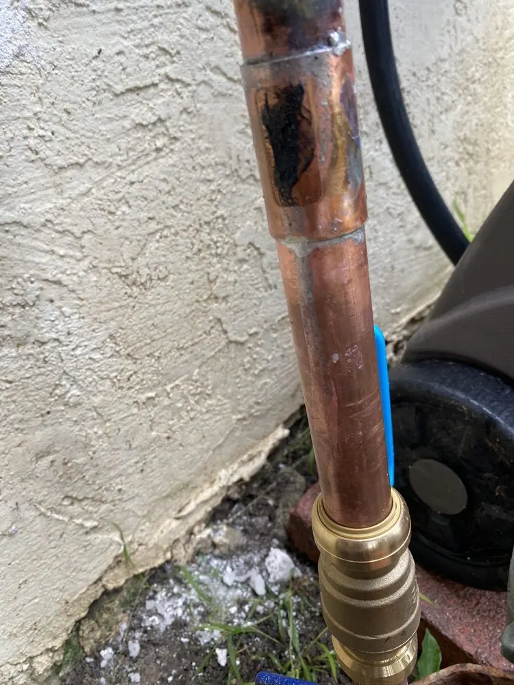 Copper water pipe with a brass hose bib fitting against a stucco wall