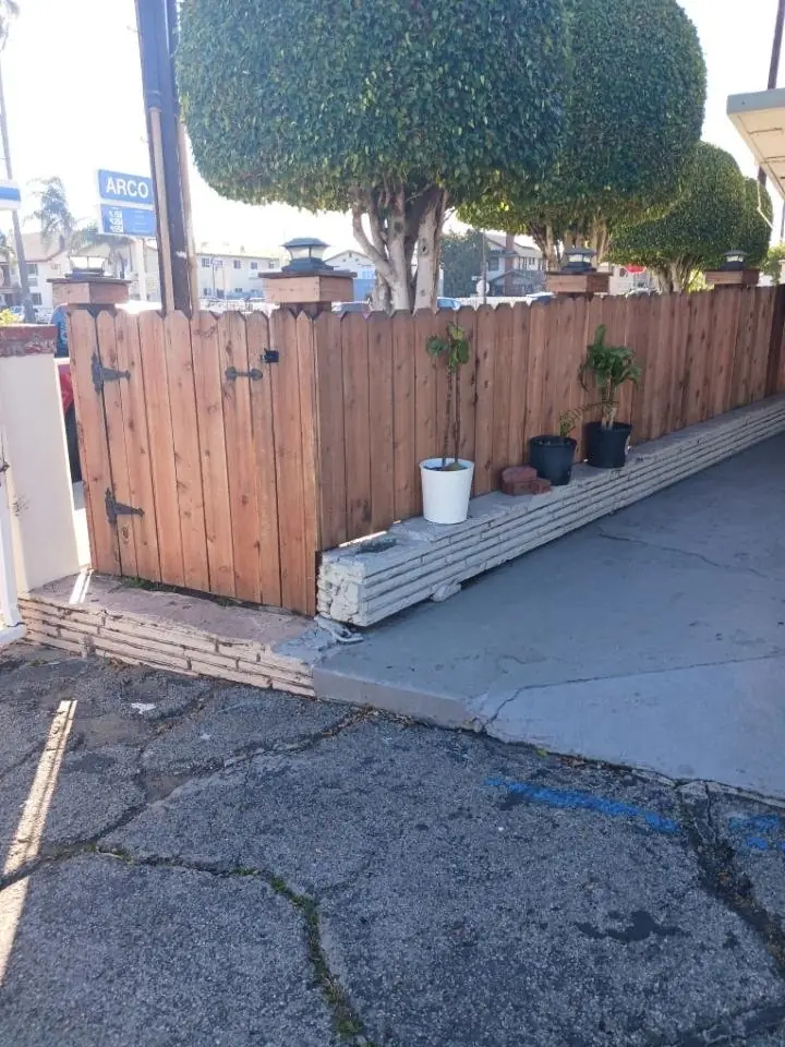 New wood fence and gate with a white planter along a driveway