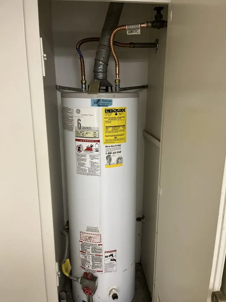Tank water heater installed in a narrow utility closet with new gas and water connections