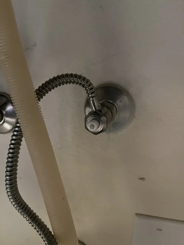 Braided supply line connected to a chrome angle stop at the wall